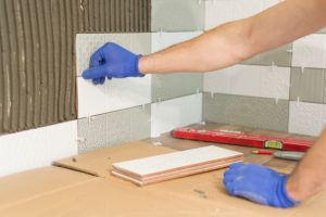 Gresham Worker Installing Tiles with blue work gloves on